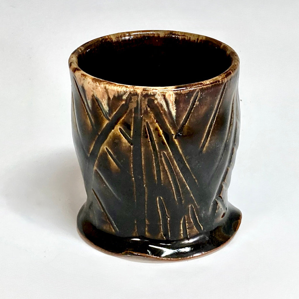 Handmade tenmoku cup with carved geometric pattern and amber rim, artisan ceramic North Carolina pottery.