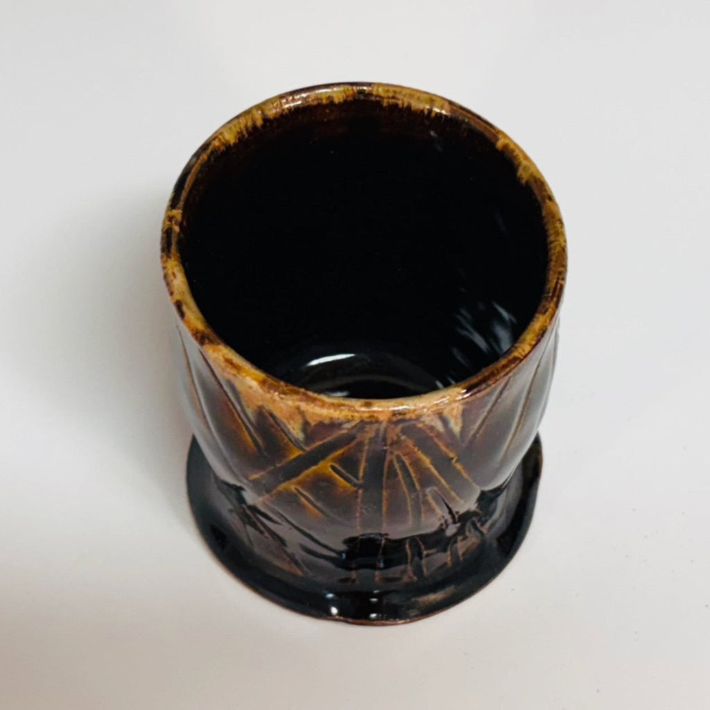Handmade tenmoku cup with carved geometric pattern and amber rim, artisan ceramic North Carolina pottery.