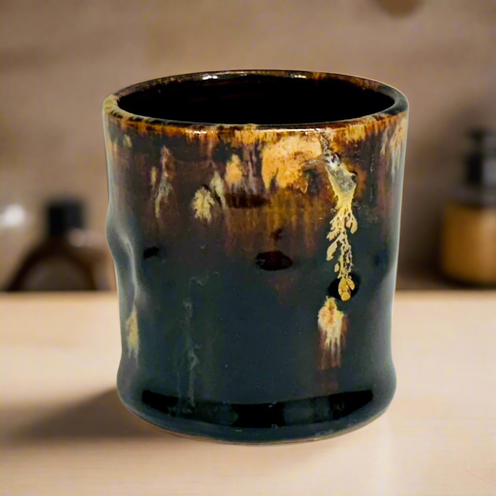A lovely brown glazed cup with a beige and amber runs on a kitchen countertop.