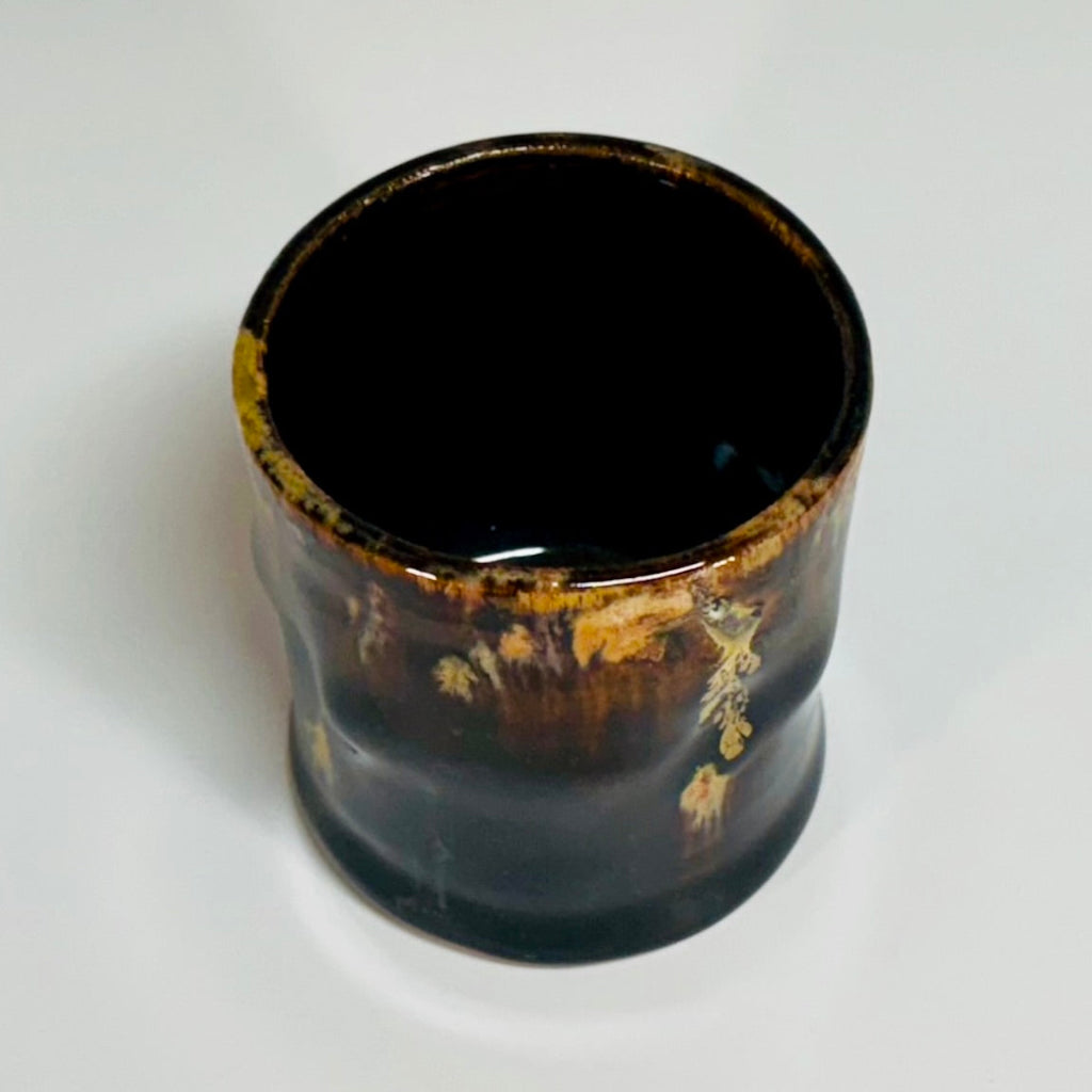 A lovely brown glazed cup with a beige and amber runs.