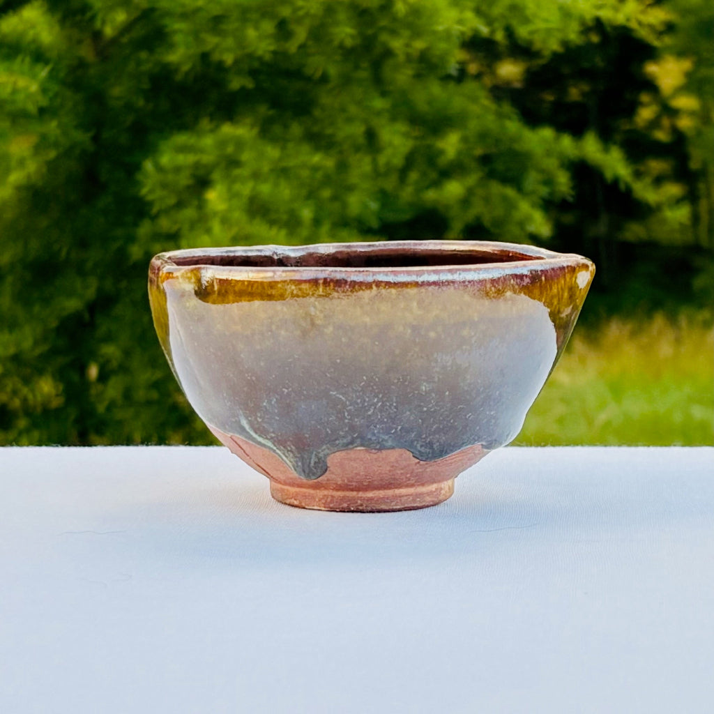 Small handmade ceramic desert bowl with amber glaze flowing over brown clay