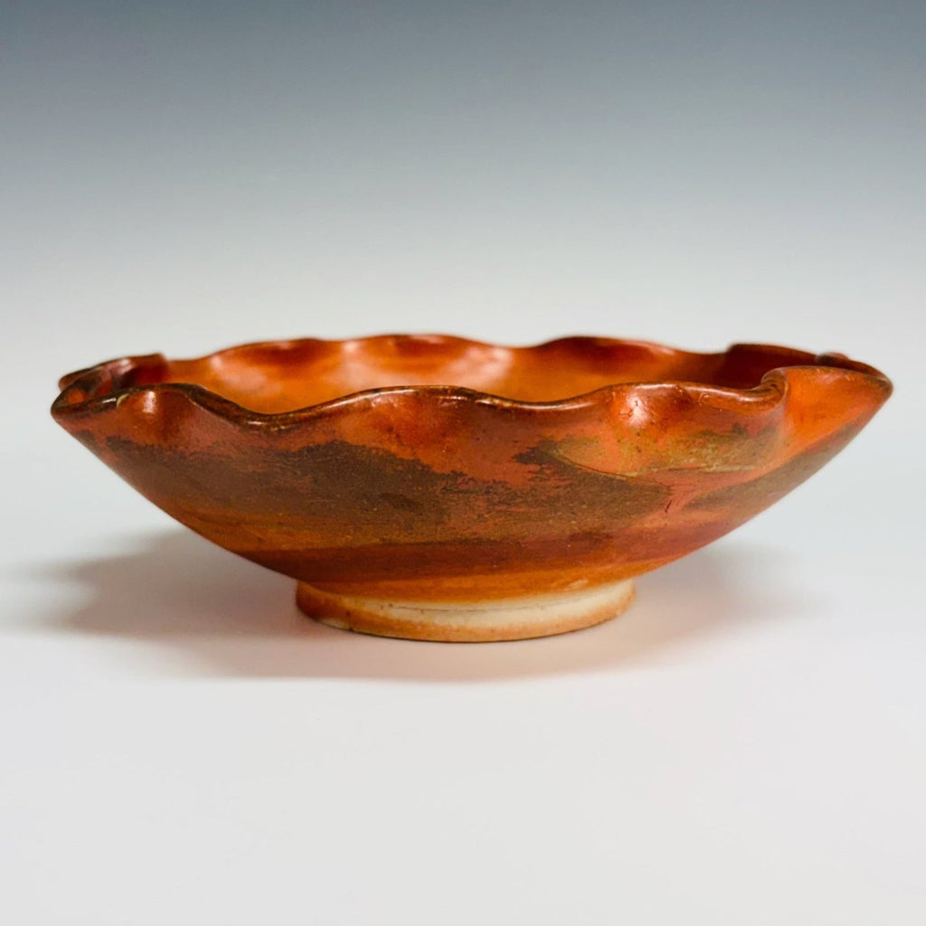 Beautiful pottery bowl with burnt orange glaze, with dark brown free form curved line decorations, small base for stability and fluted edge. 