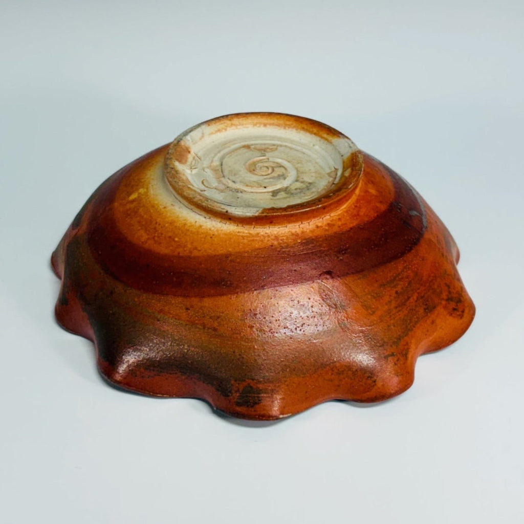 Beautiful pottery bowl with burnt orange glaze, with dark brown free form curved line decorations, small base for stability and fluted edge. 