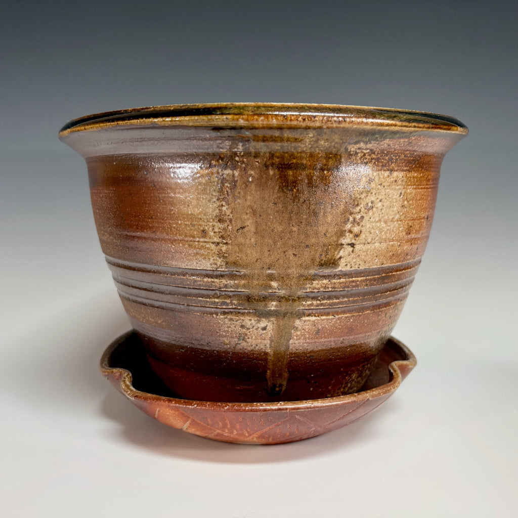 Artisan ceramic planter with amber and bronze glaze, hand-thrown in North Carolina with complementary drainage tray.