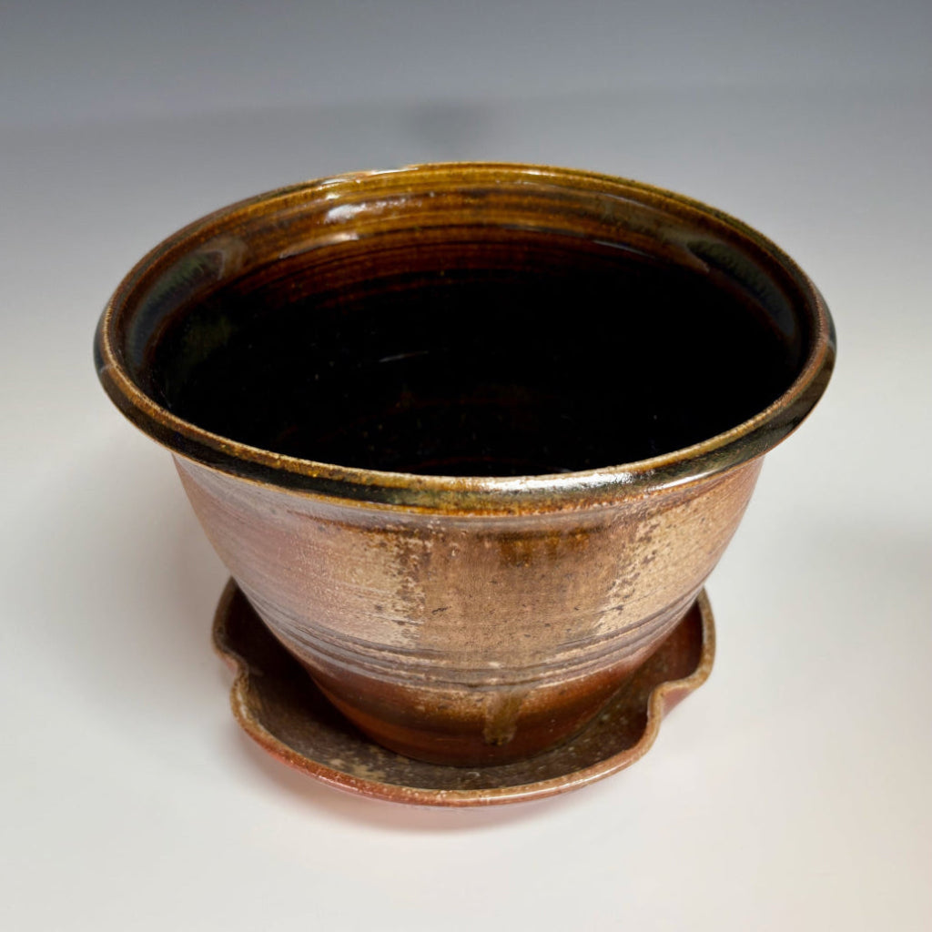 Artisan ceramic planter with amber and bronze glaze, hand-thrown in North Carolina with complementary drainage tray.