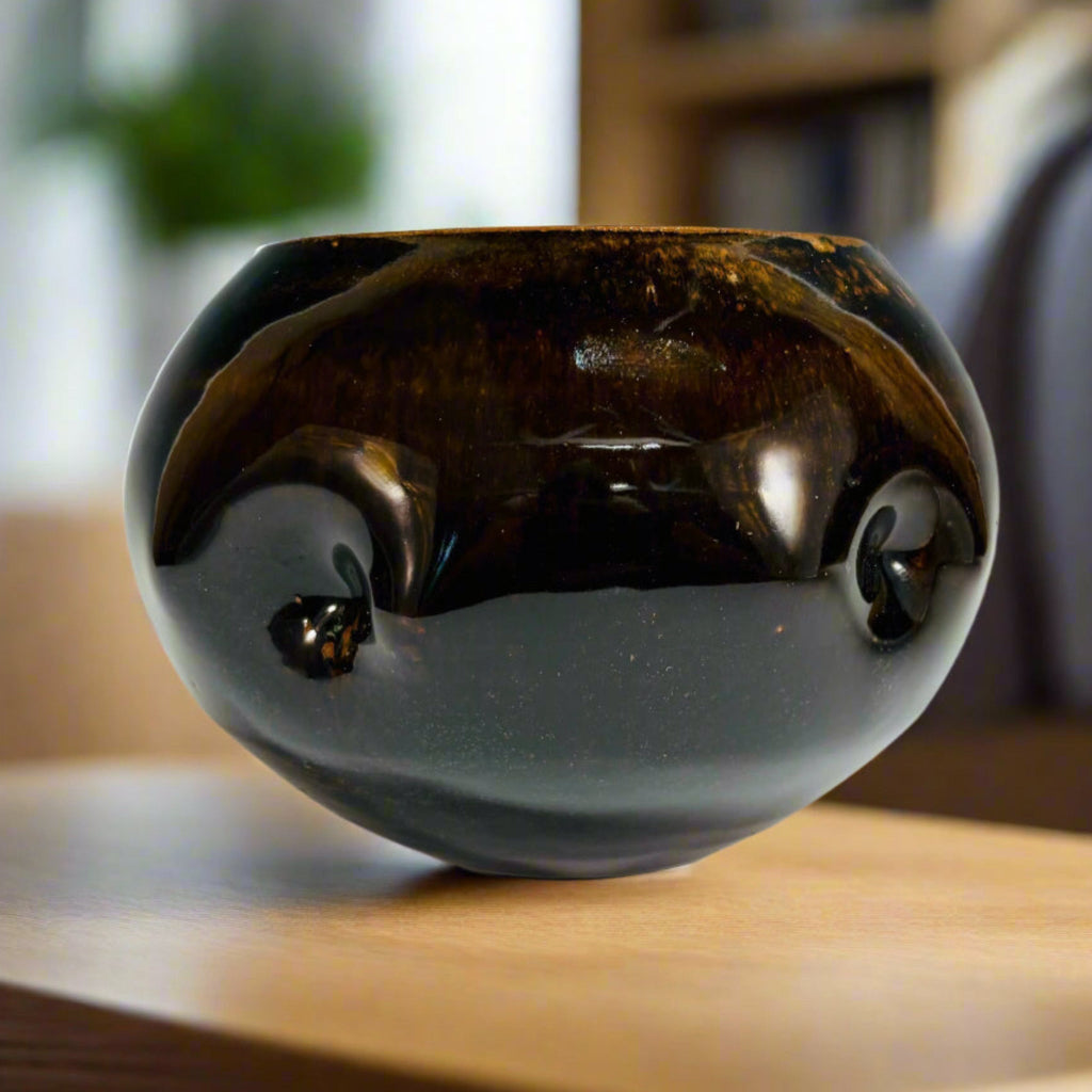 Round chestnut glazed vase with tactile dimpled surface on a wooden kitchen counter, handmade and wood-fired in Danbury, NC