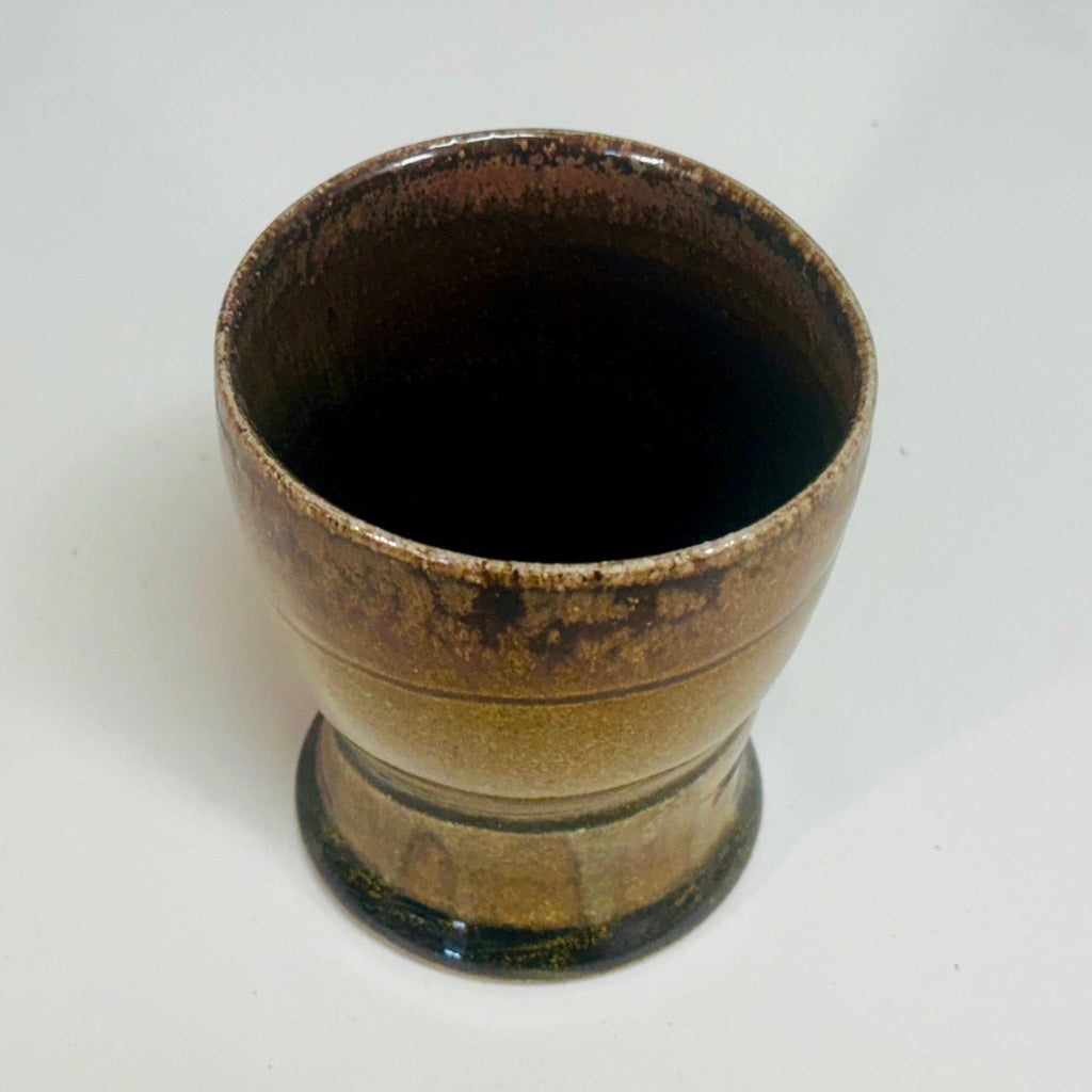 Handcrafted wood-fired ceramic tumbler with delicate greenish brown to chocolate transitions and horizontal banding.