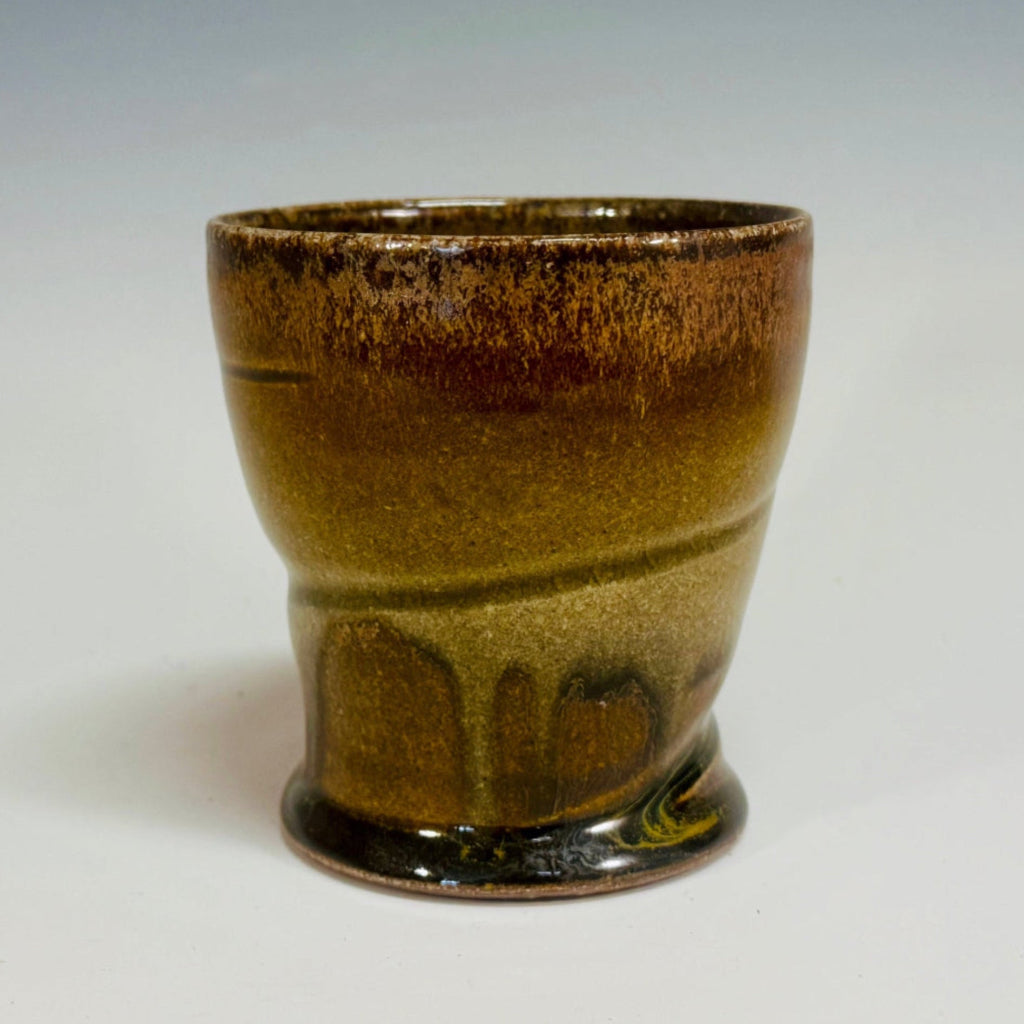 Handcrafted wood-fired ceramic tumbler with delicate greenish brown to chocolate transitions and horizontal banding.