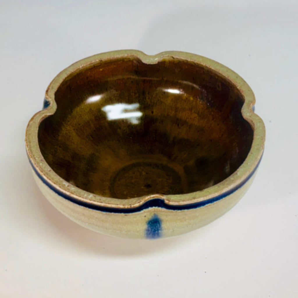 Handcrafted wood-fired ceramic bowl with cream body, cobalt blue vertical streaks, rich brown interior, and earthy brown foot, made by artisans in Danbury, NC.