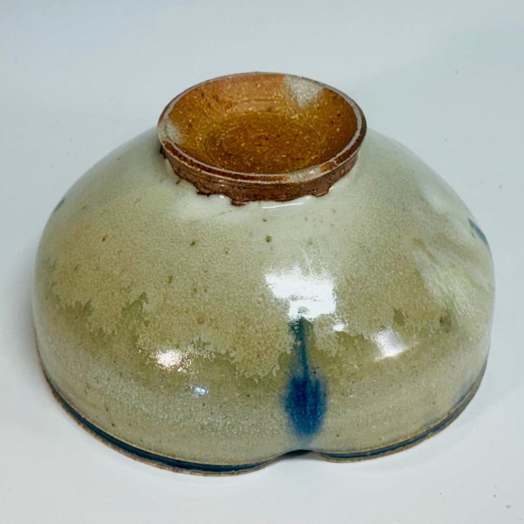 Handcrafted wood-fired ceramic bowl with cream body, cobalt blue vertical streaks, rich brown interior, and earthy brown foot, made by artisans in Danbury, NC