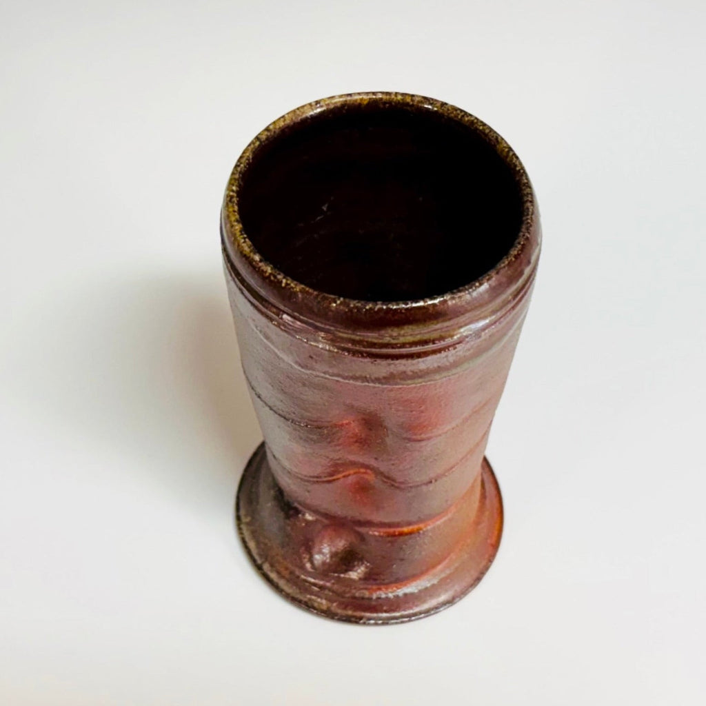 handcrafted wood-fired stoneware tumbler with horizontal ridges and rich mahogany glaze