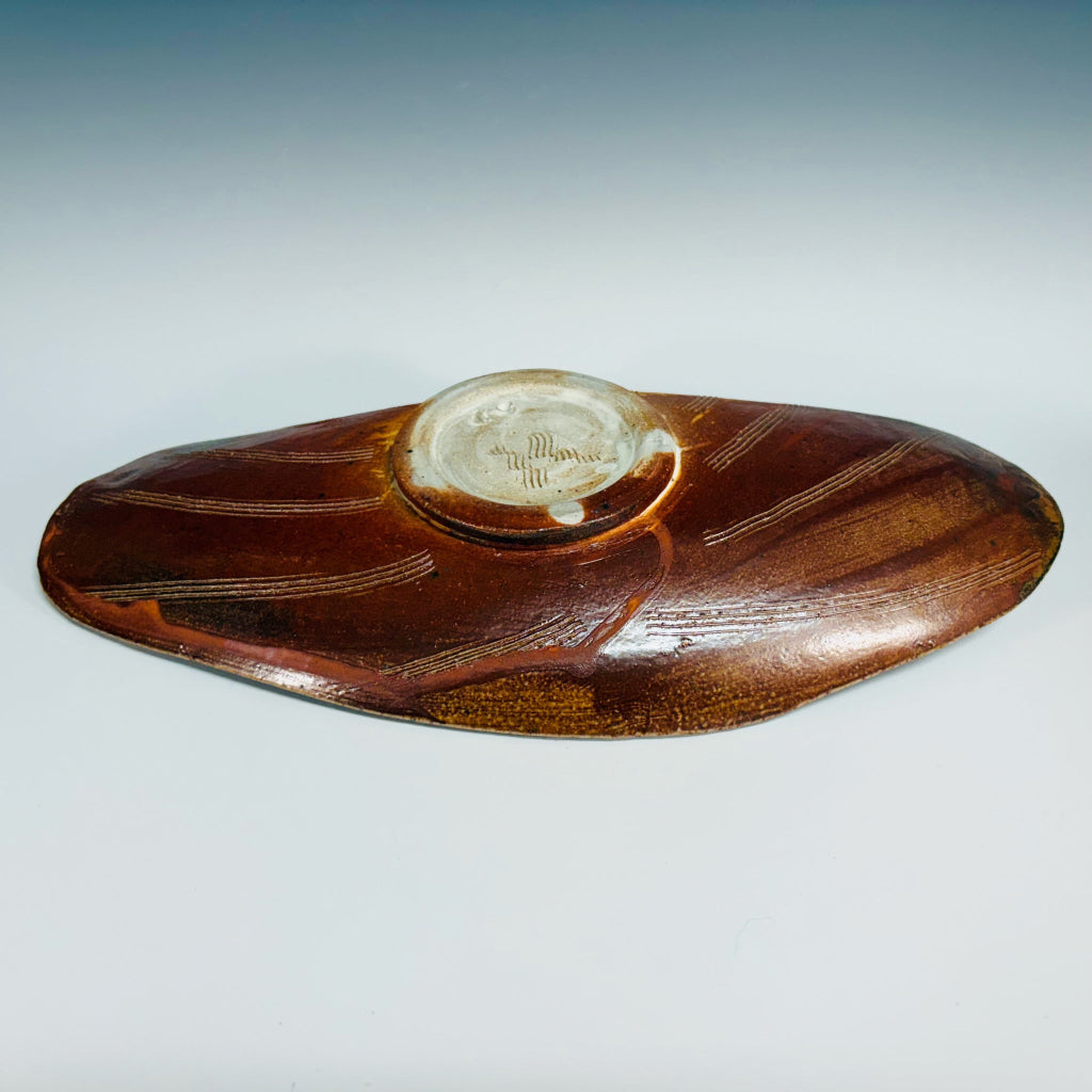 Bottom view: Handmade elongated oval serving tray with natural wave patterns in earthy brown tones and a circular base.