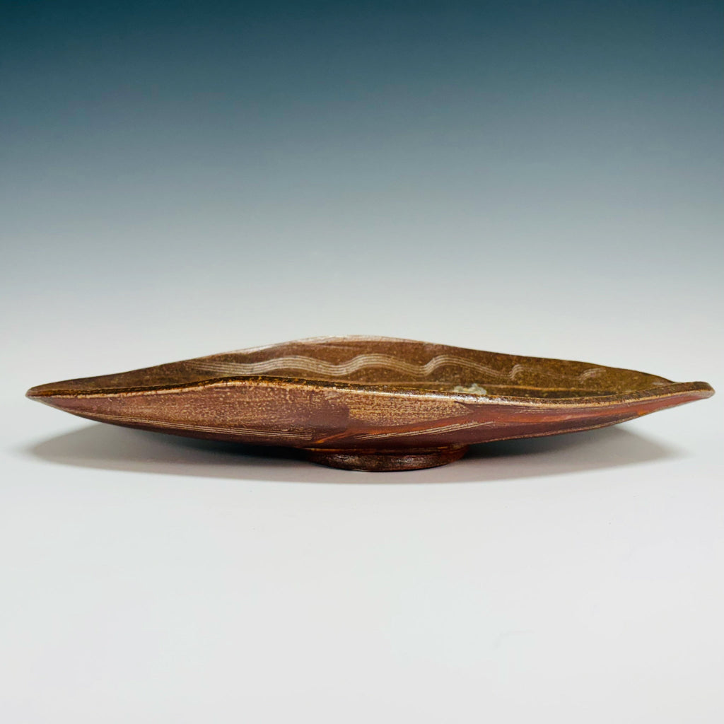 Handmade elongated oval serving tray with natural wave patterns in earthy brown tones, wood-fired in North Carolina.