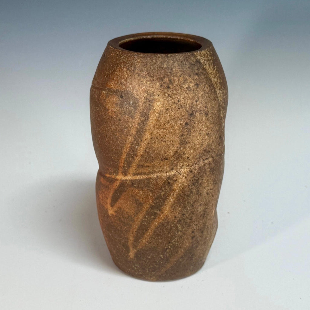 Handcrafted wood-fired ceramic vase in vibrant orange with natural ash deposits and horizontal banding.