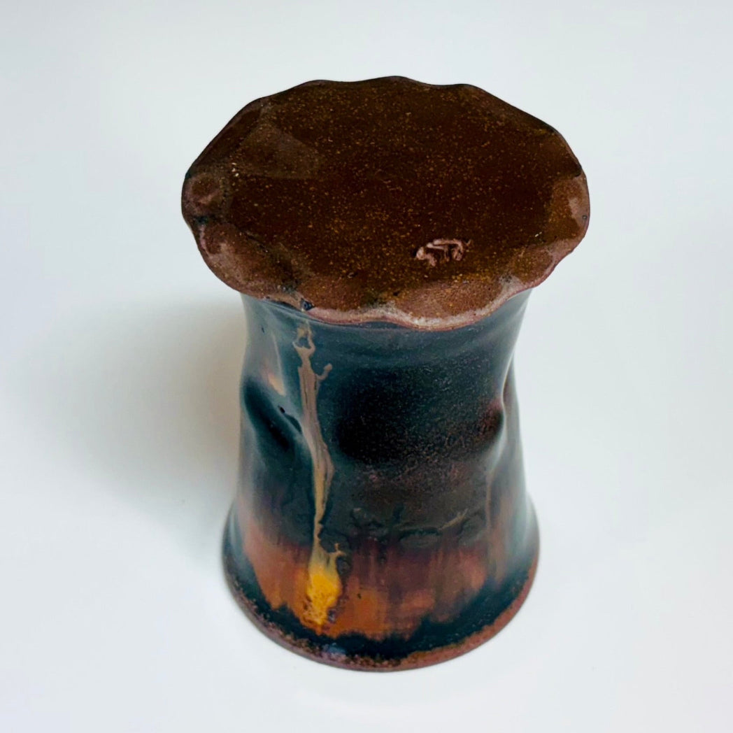 This cup is a handcrafted wood-fired cup with dark brown/black glaze with amber drip and speckled rim.
