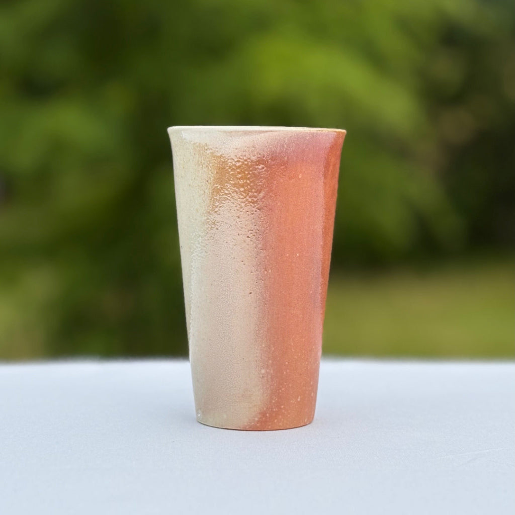 Side view: handmade wood-fired porcelain cup by Sam Dougherty with pink gradient finish, unglazed exterior, and white interior glaze. Made in Danbury, NC Studio. 