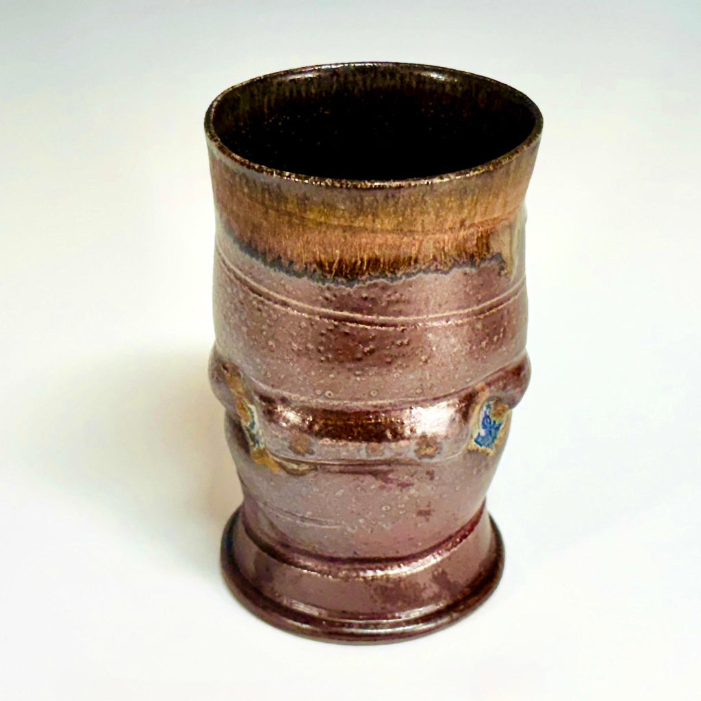 Hand-thrown ceramic tumbler with amber rim gradient and chocolate brown body from wood-firing.