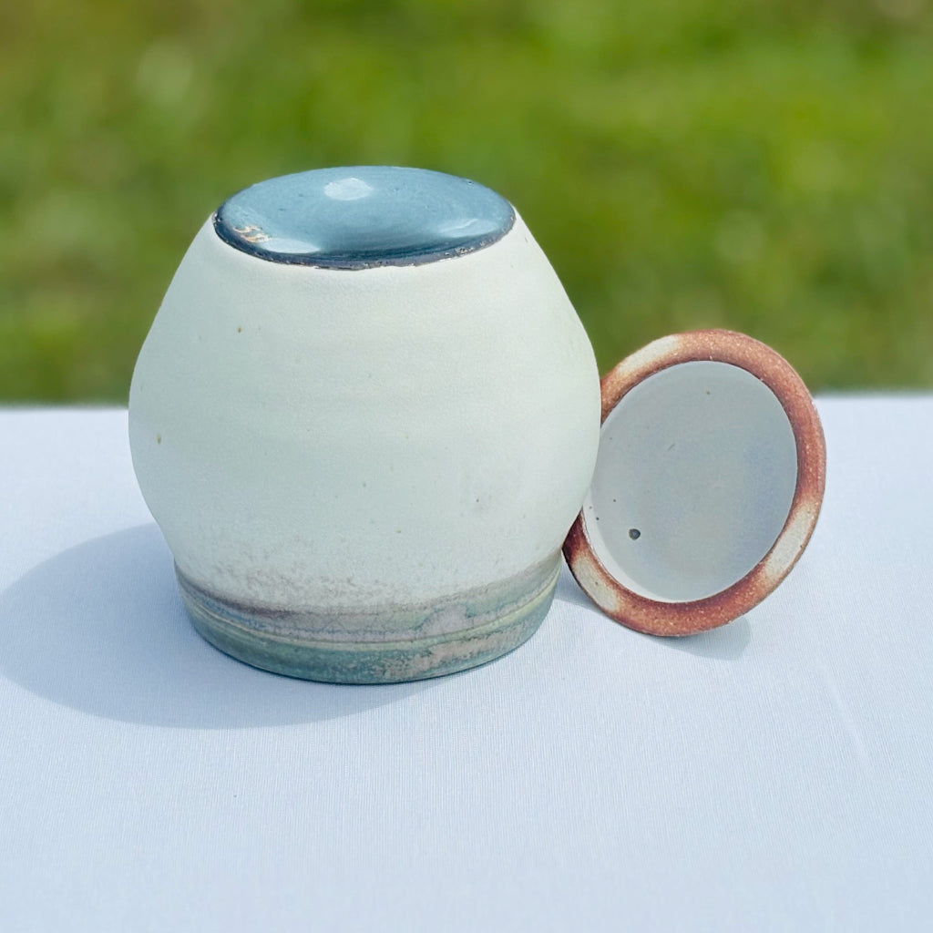 Bottom view: Lovely round pottery jar with a black bottom and artist's mark and lid interior with an amber and white rim made in Danbury, NC.