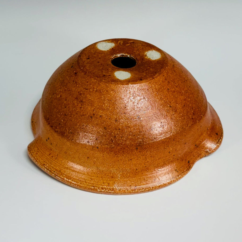 bottom view of artisan amber stoneware planter showing amber glaze pattern and drainage hole.