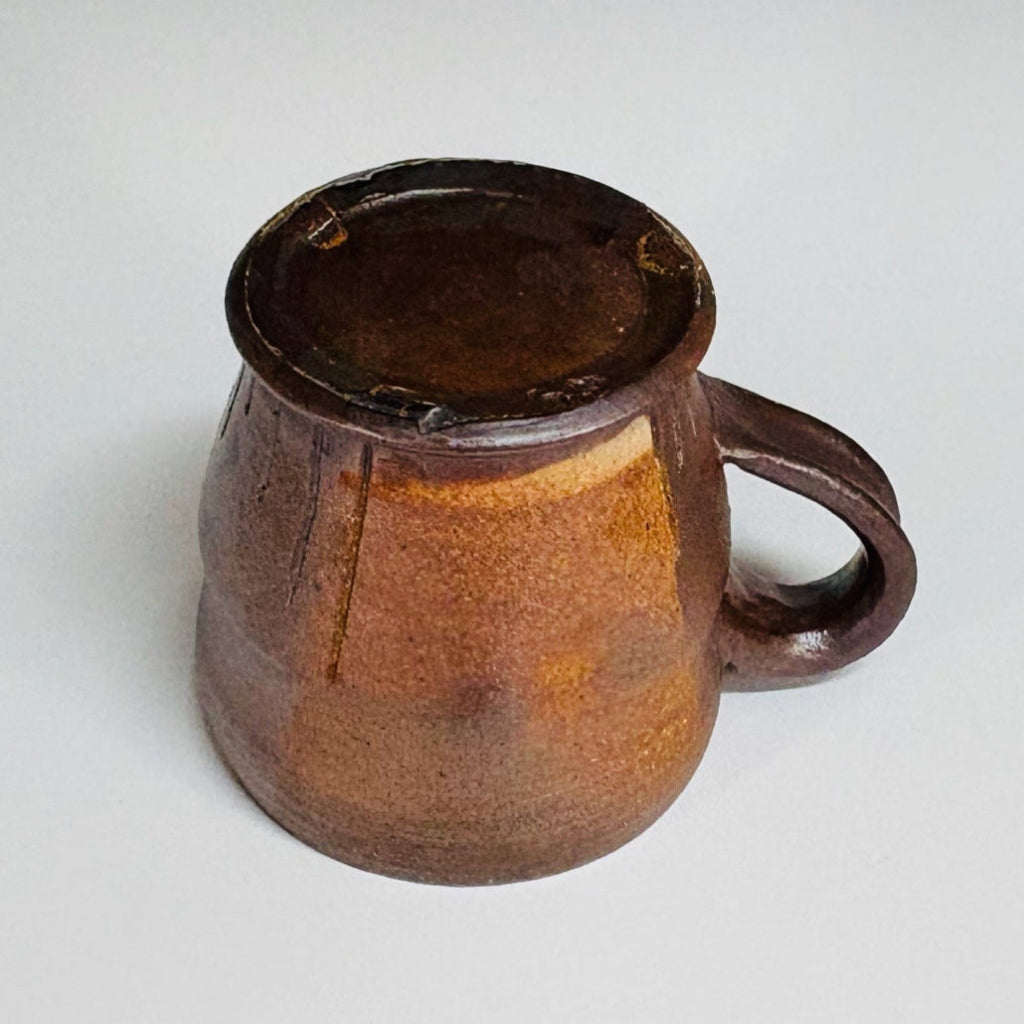 Handcrafted wood-fired brown stoneware mug with white interior and curved handle from Danbury pottery