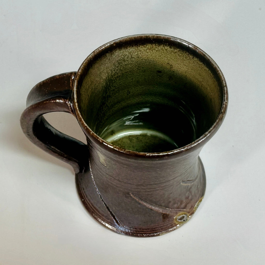 Inside view of handmade wood-fired pottery mug showing olive green glaze and artisanal craftsmanship.