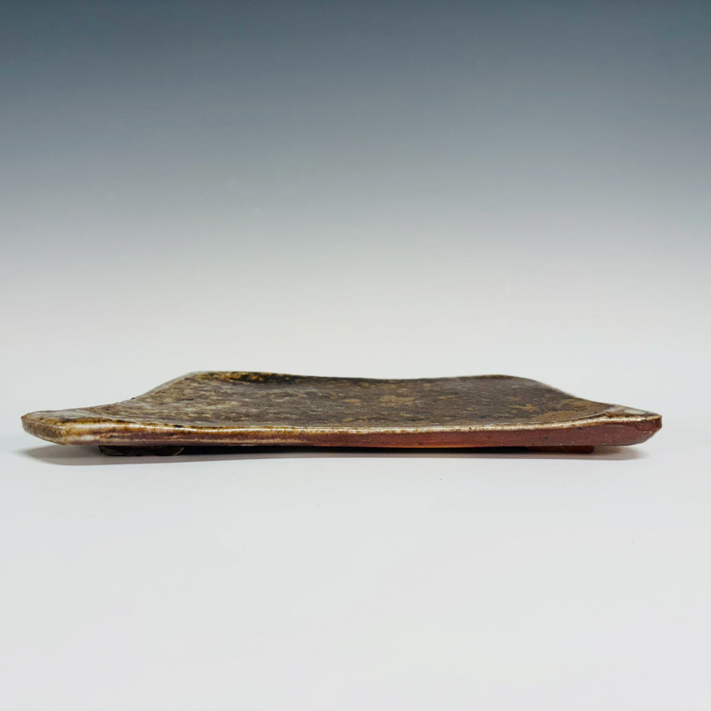Handmade earth-tone stoneware soap dish with natural speckled texture and slightly raised edges.
