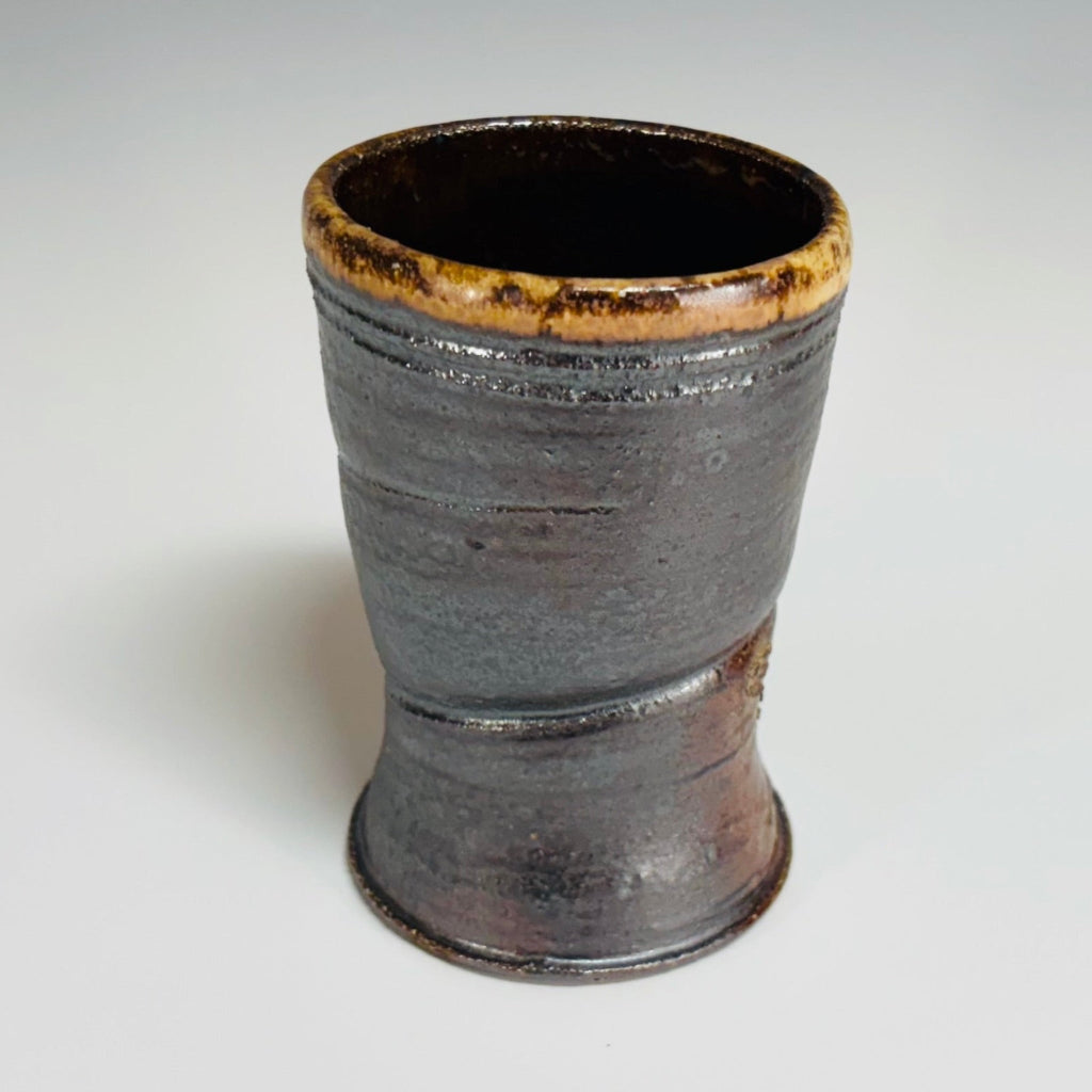 Profile view of handcrafted wood-fired ceramic tumbler with charcoal exterior and golden-brown glazed rim, made in Danbury, NC.