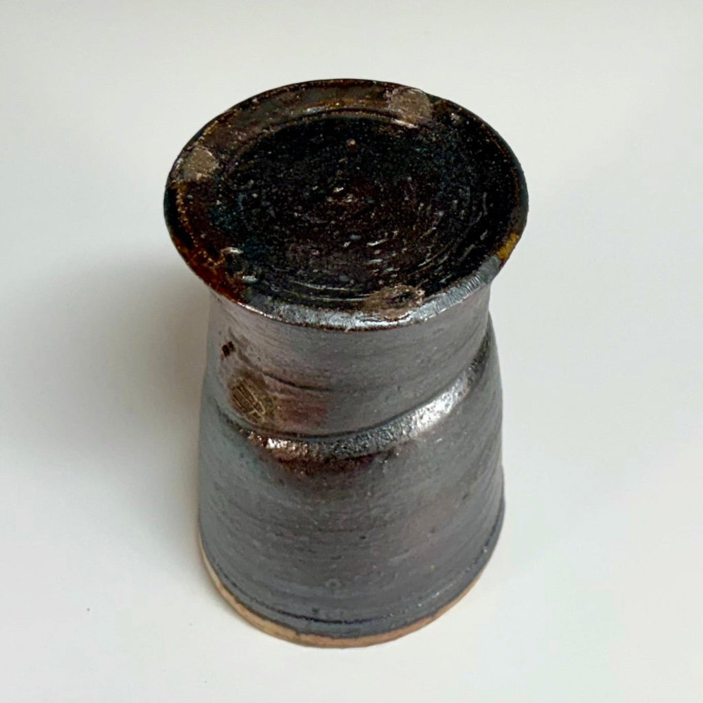 Bottom view of handcrafted wood-fired ceramic tumbler with charcoal exterior and golden-brown glazed rim, made in Danbury, NC.