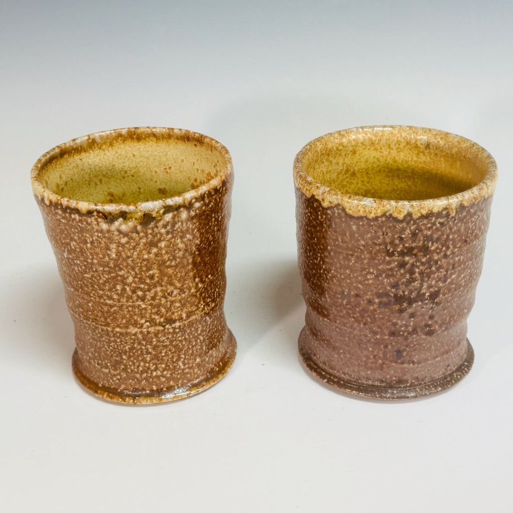 Pair of handcrafted wood-fired ceramic tumblers with sandy textured exterior and warm golden interior glaze