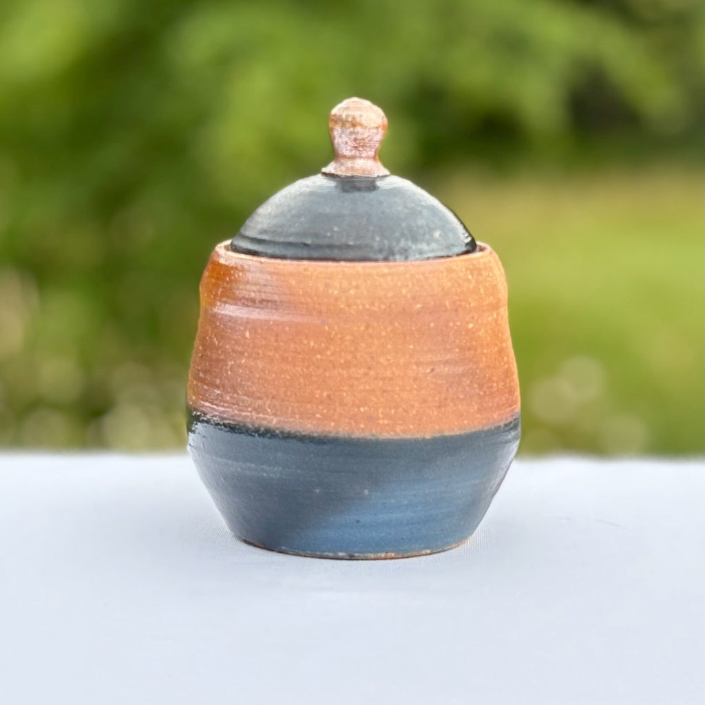 Small handmade ceramic peacock jar with blue-green slip and natural brown clay body