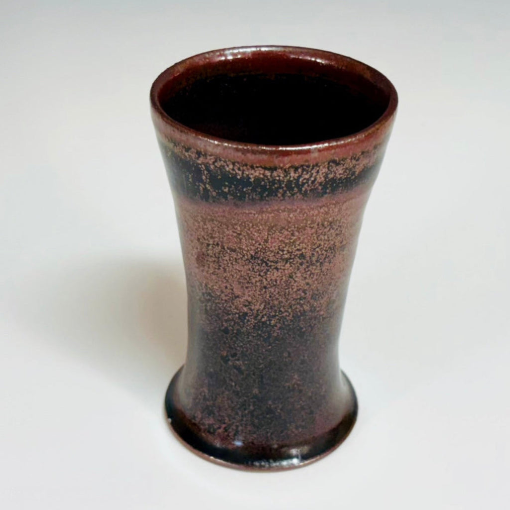 Top view: Handcrafted wood-fired cup with red/pink speckles and flared rim and a reddish/pink/brown interior.