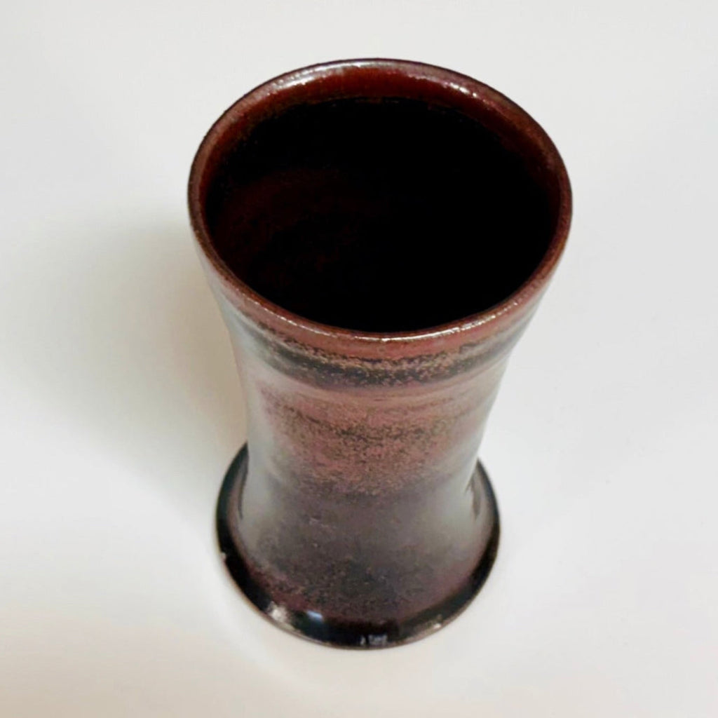 Top view: Handcrafted wood-fired cup with red/pink speckles and flared rim and a reddish/pink/brown interior.