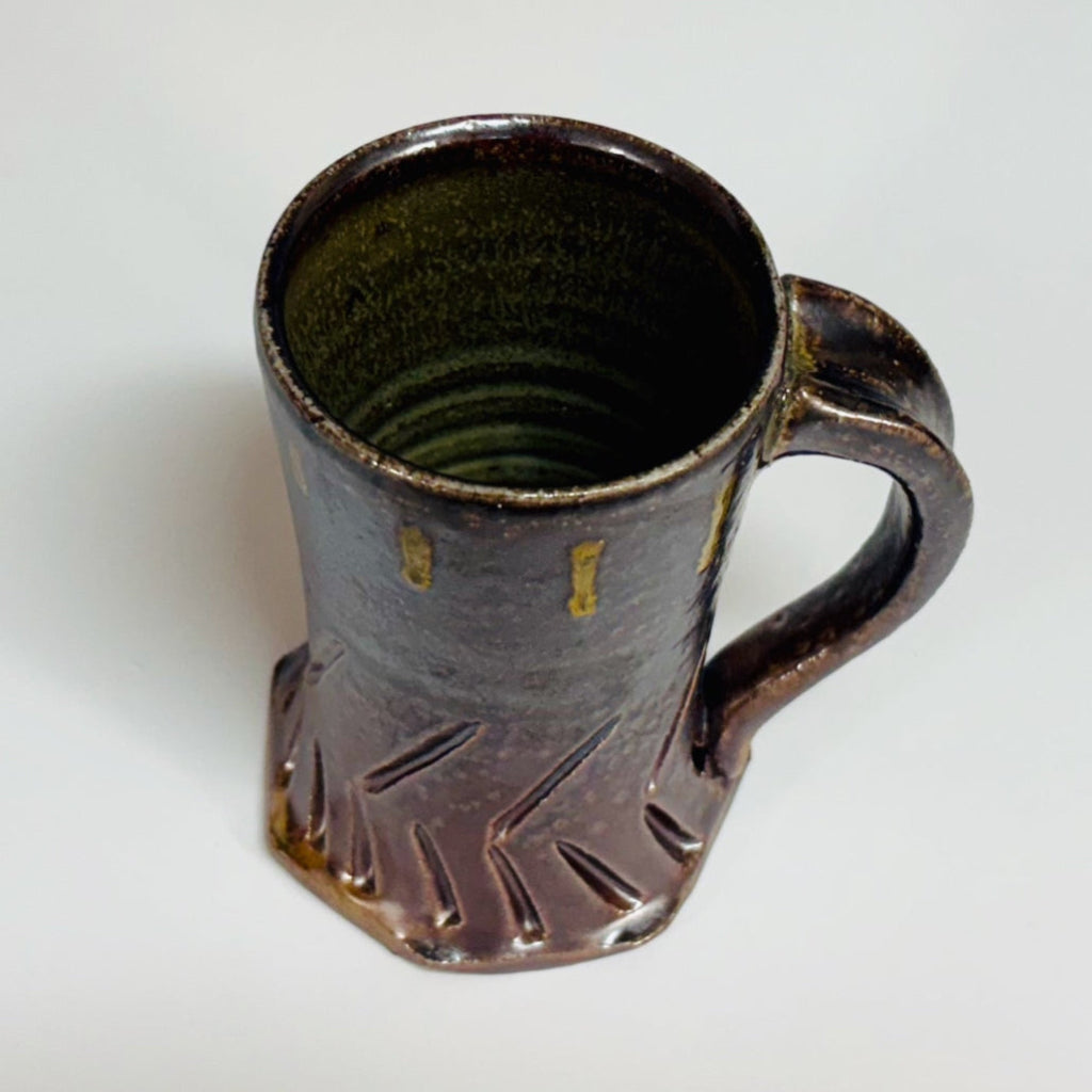 Interior view. Handcrafted gray stoneware mug with carved chevron pattern, amber glaze drips and curved handle.