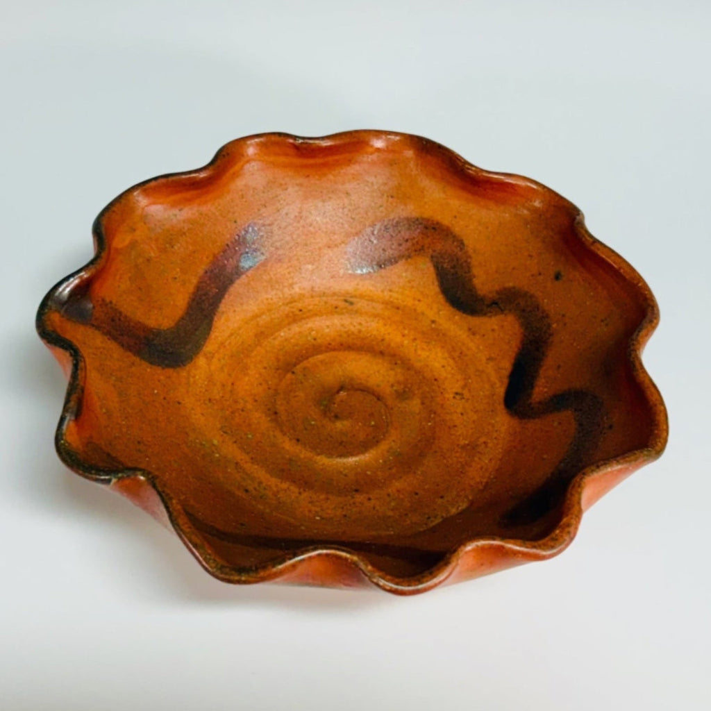 Beautiful pottery bowl with burnt orange glaze, with dark brown free form curved line decorations, small base for stability and fluted edge. 