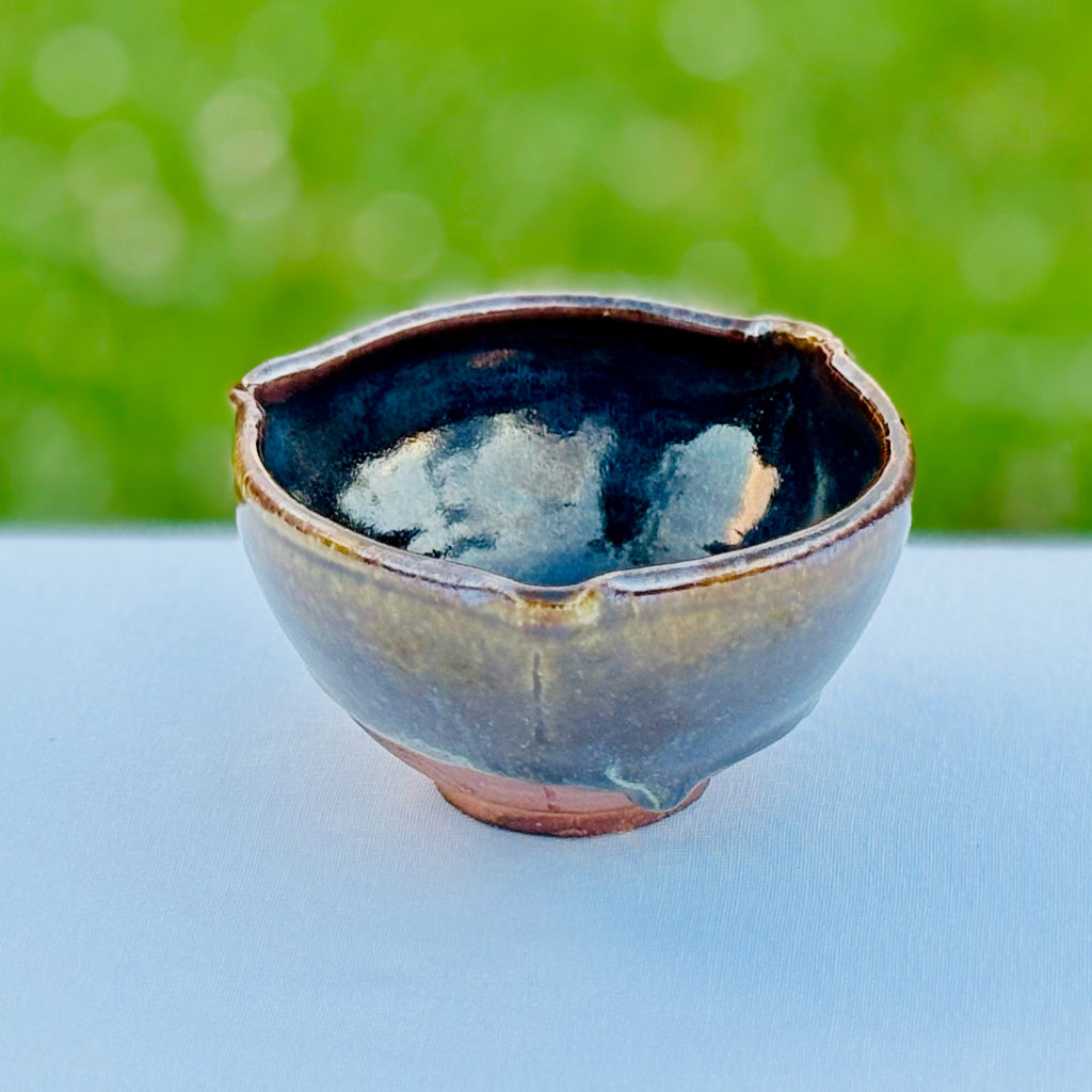 Ceramic bowl with a textured surface on a white surface with a blurred green background