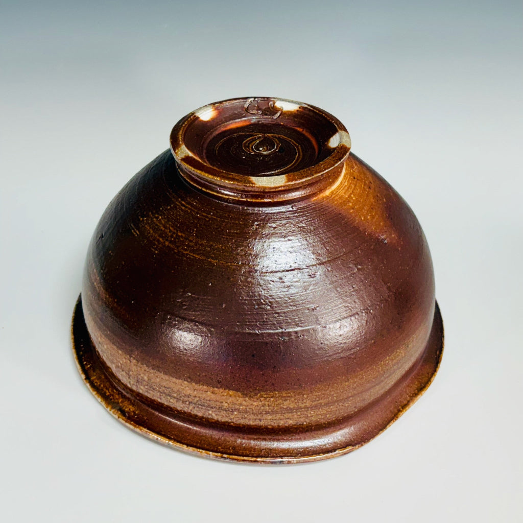 bottom view handcrafted amber and brown speckled stoneware serving bowl with stable stable base.
