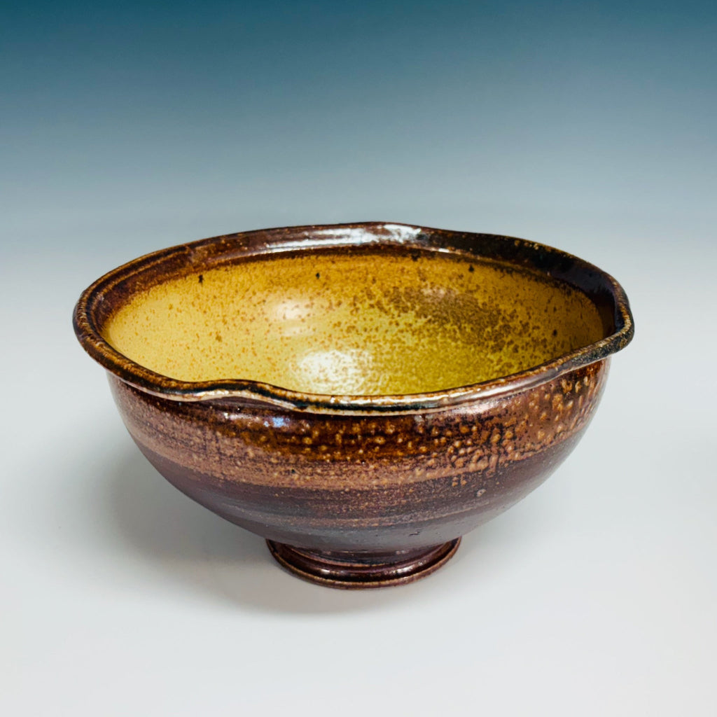 Handcrafted amber and brown speckled stoneware serving bowl with smooth interior and textured gradient exterior.