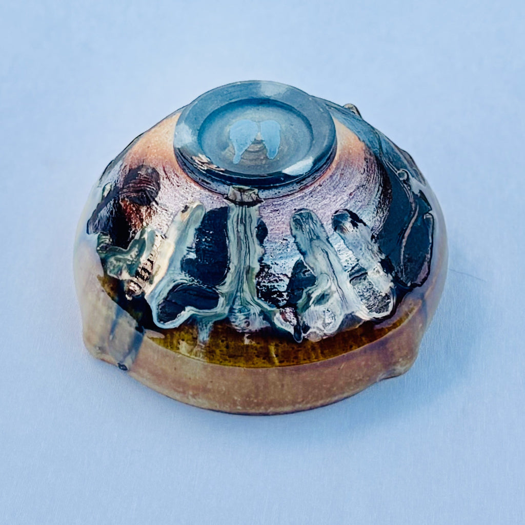 Ceramic bowl with unique glaze patterns on a white background