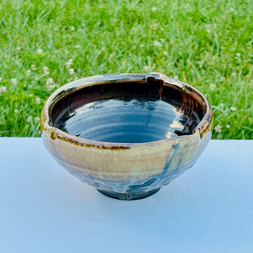 Ceramic bowl with a textured surface on a white surface with grass in the background
