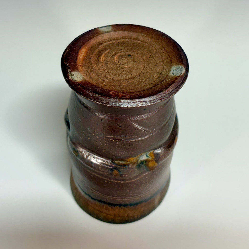 hand-thrown ceramic tumbler with an unglazed bottom with a carved swirl and three dots