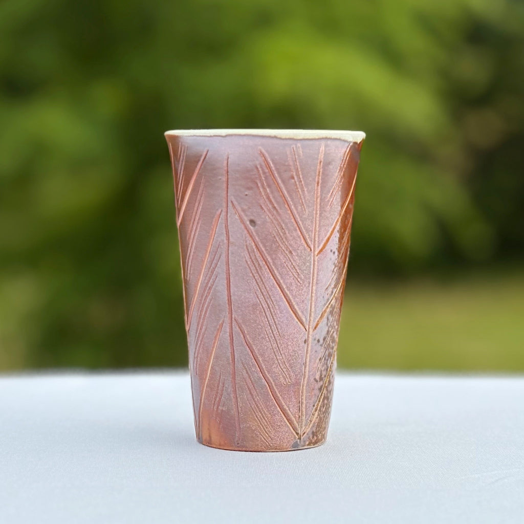 Porcelain cup made in NC featuring a brown exterior and white interior and hand carving 