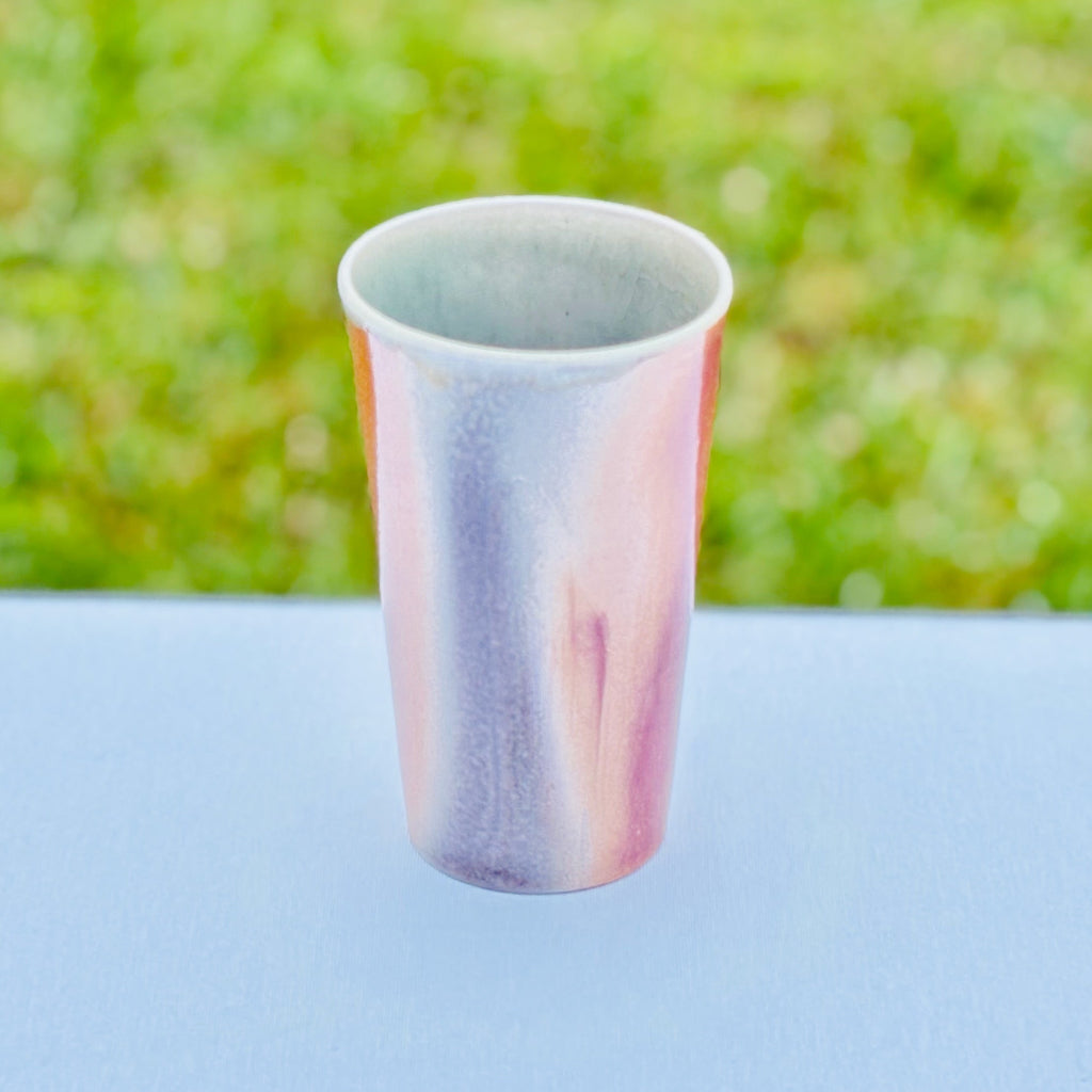 Handmade wood-fired porcelain cup by Sam Dougherty with soft gray blush and pink/peach gradient finish, unglazed exterior, and white interior glaze.