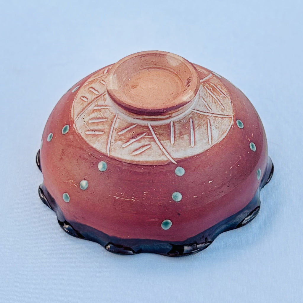 Handcrafted ceramic bowl showing pottery foot ring, abstract carving design, green glaze dots, and wood fired clay