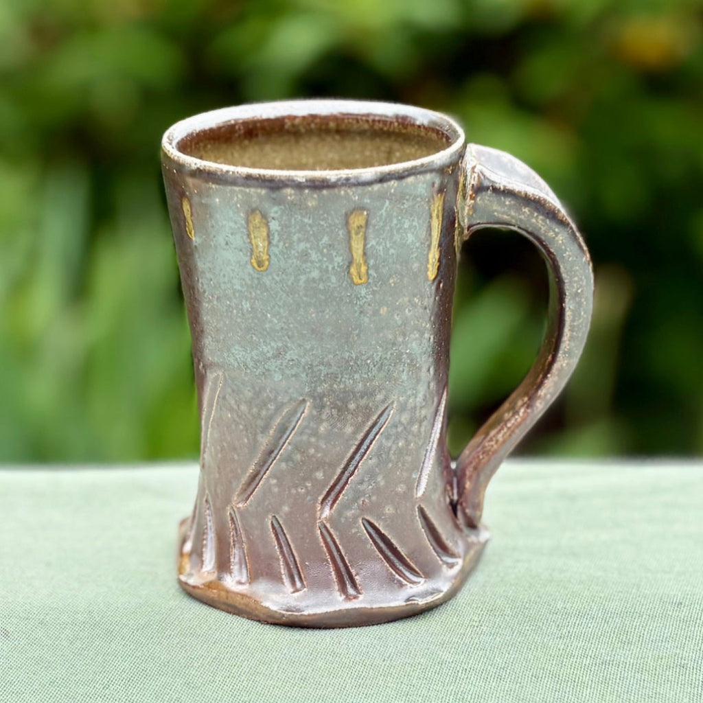 Ceramic mug with brown color and gold glaze dots, featuring an elongated shape with opposing lines and a hexagonal base