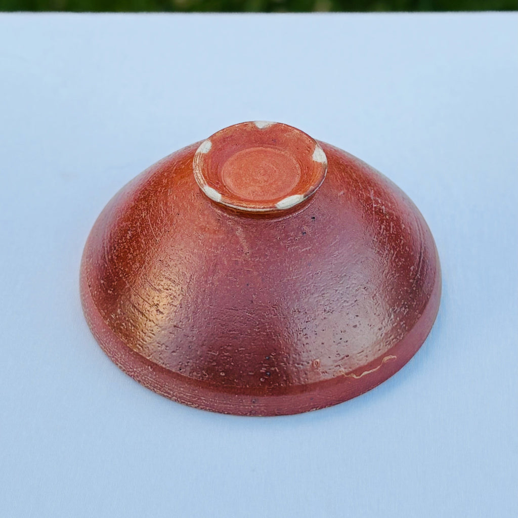 handcrafted shiny amber ceramic bowl showing pottery foot ring with five white dots