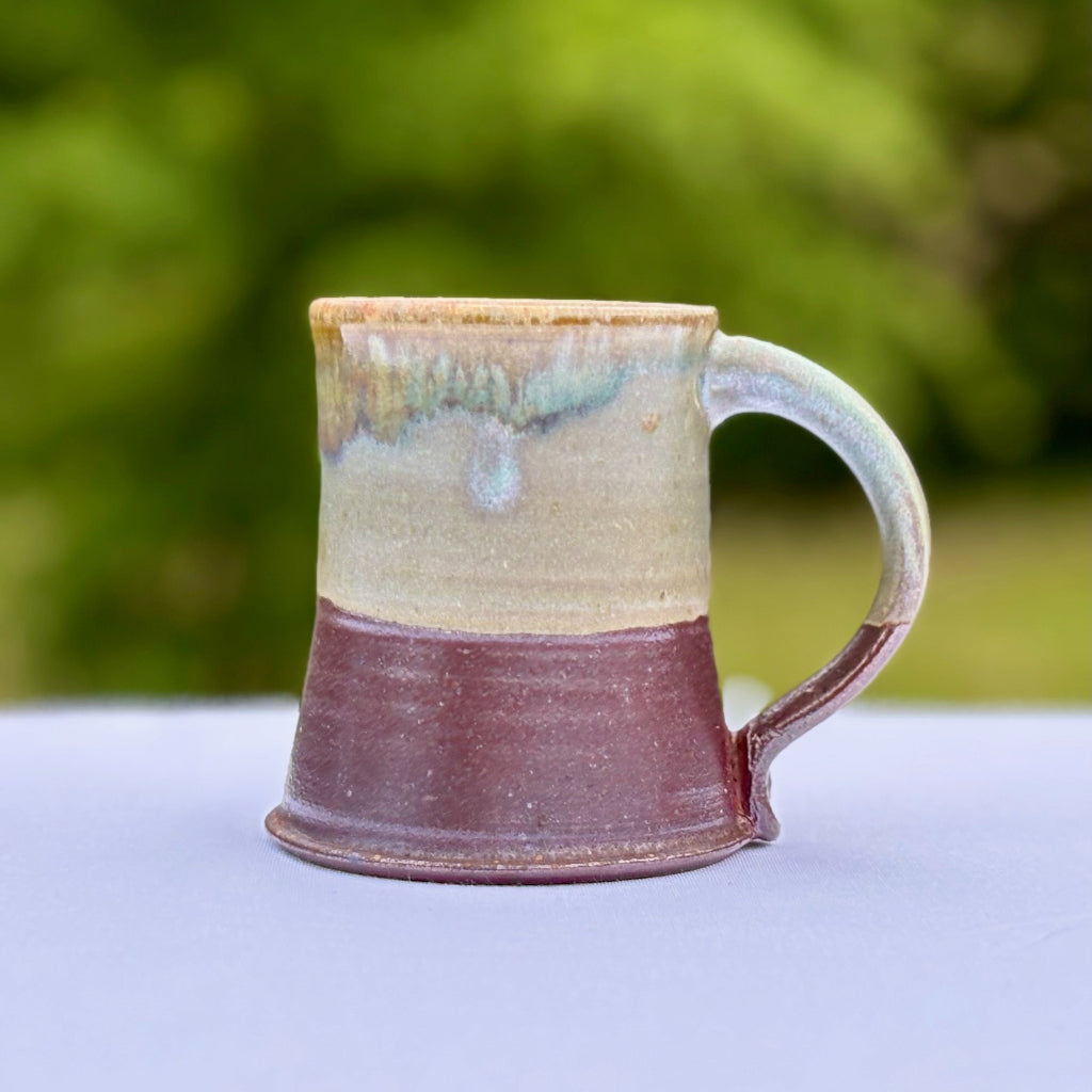 Oribe ceramic mug with an unglazed, earthy lower half and variegated green runs from the rim