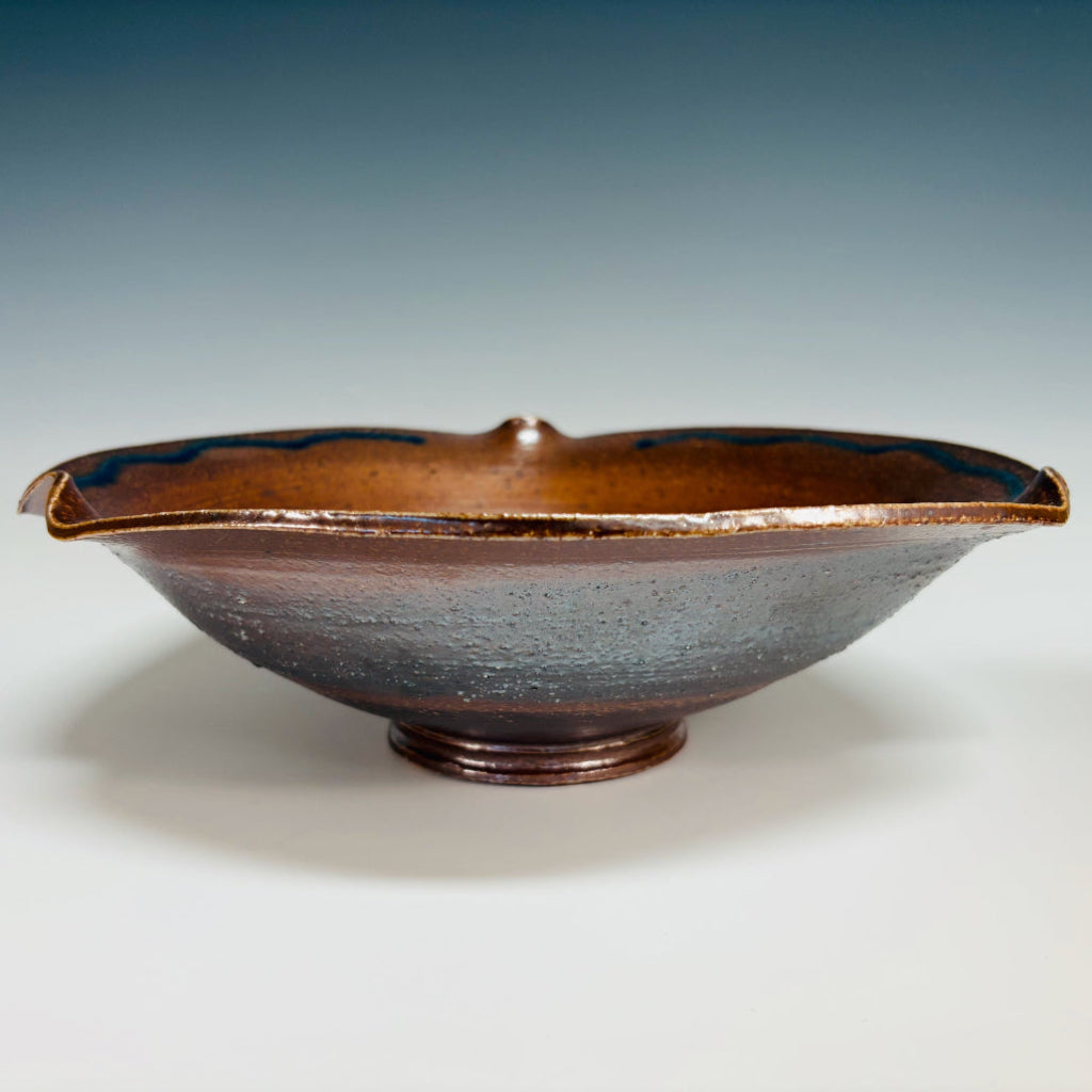 Side view: Handcrafted ceramic serving bowl with wavy rippled edge.
