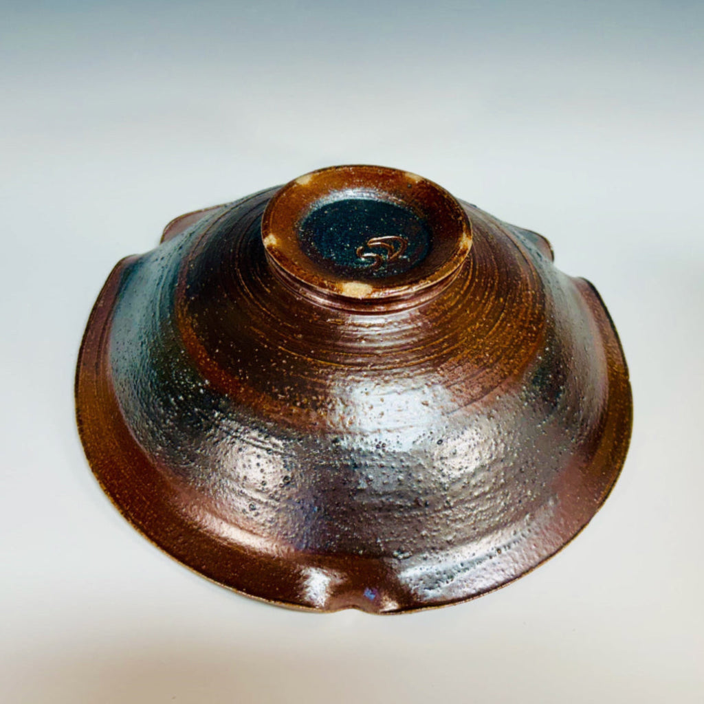 Bottom view: Handcrafted ceramic serving bowl with wavy rippled edge, and warm brown glaze on exterior.