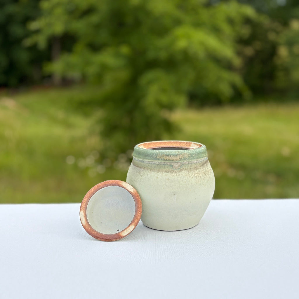 Lovely round pottery jar with lid removed and a natural interior rim and light green glaze inside