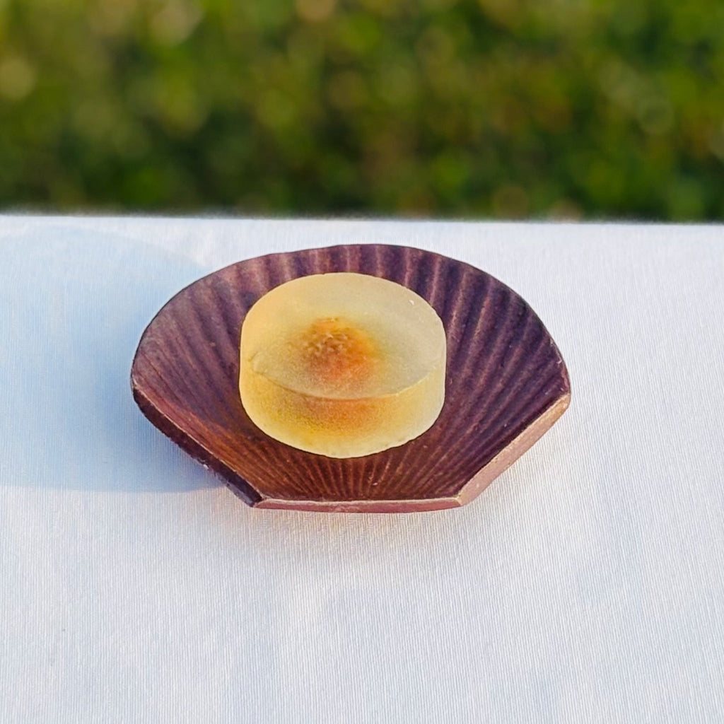 Top view of scallop shell pottery soap dish showing wood-fired natural glazing and texture details with a clear round soap in the middle